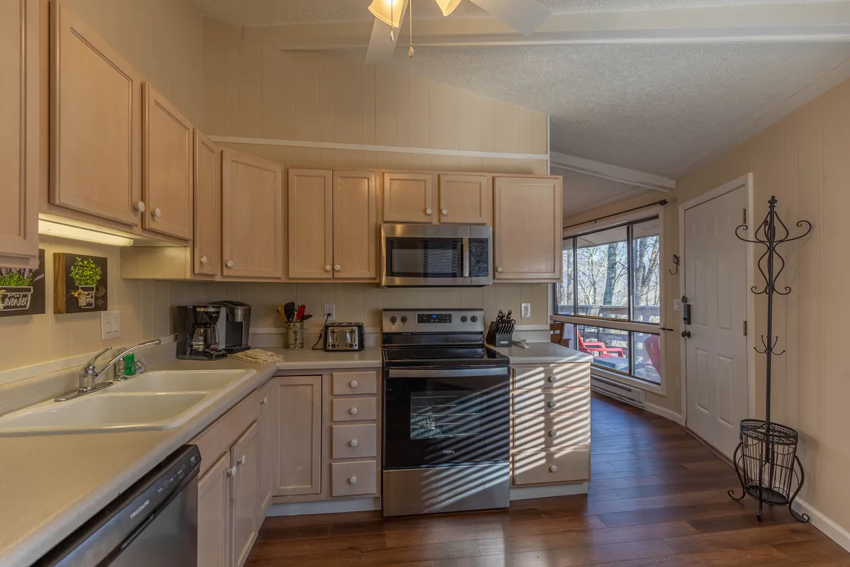 A view of the kitchen with stainless steel appliances and ample cabinet storage, highlighted by a window that frames a scenic outdoor view. The setting feels warm and welcoming, ideal for both cooking and spending time with loved ones.
