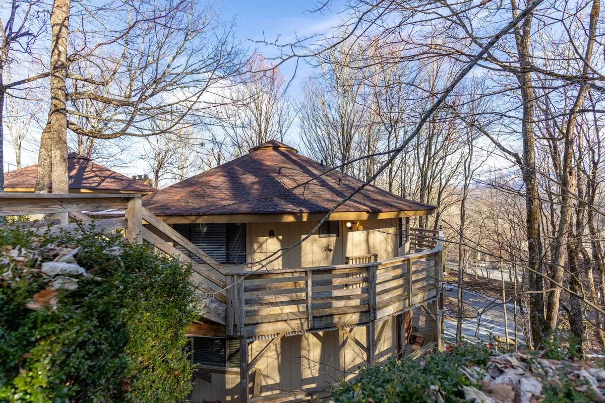 This photo highlights a spacious wooden deck with a circular roof, nestled among tall trees. The setting hints at leisurely afternoons spent relaxing outdoors, watching sunsets, or setting out for nearby hiking trails.